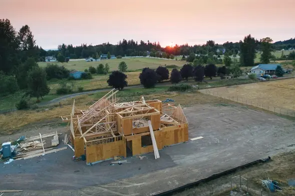 Construcción sostenible mediante soluciones CleanTech. Vista aérea de una casa de madera en construcción al atardecer utilizando prácticas de construcción sostenible.
