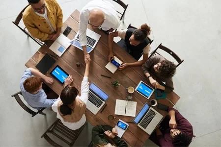 Équipe collaborant autour d’une table avec des ordinateurs portables et des outils numériques, concentrée sur des solutions durables.