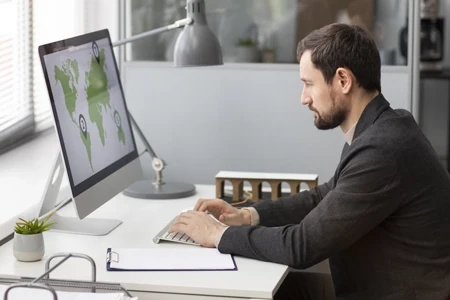 Homme analysant les opportunités du marché mondial sur un écran d’ordinateur dans un espace de travail moderne.