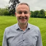 Daniel Eskenazi, director de marketing, sonriendo al aire libre en un parque verde.