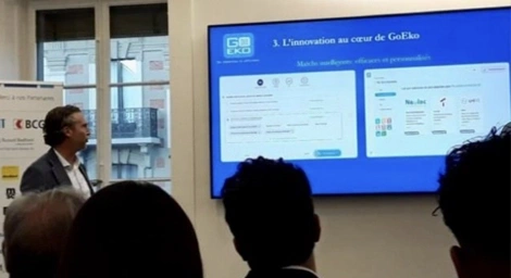 Raphaël Herrera presenting the GoEko platform at an event, standing next to a screen displaying a product demo.