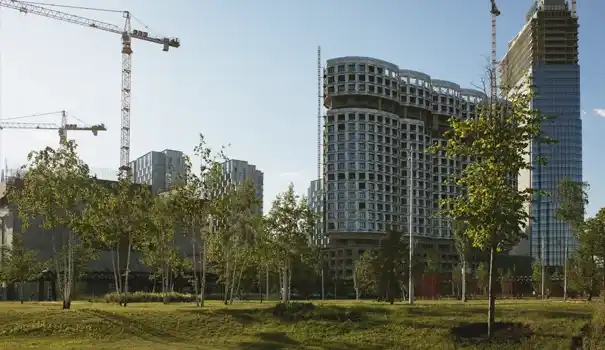 Gestión más inteligente de los edificios a través de la sostenibilidad. Modernos edificios de gran altura en construcción rodeados de árboles y grúas.