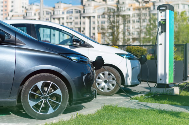 Voitures électriques en charge à une station publique pour la réduction du carbone. Deux voitures électriques connectées à une station de charge en milieu urbain.