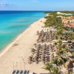 Vista aérea de resort Iberostar con playa de arena blanca y sombrillas de palma.